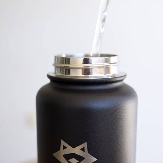Wasser wird durch die weite Öffnung in eine schwarze PARATITO Sportflasche eingefüllt